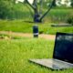 Laptop placed on green grass in a park setting, ideal for remote work and digital nomad lifestyle.