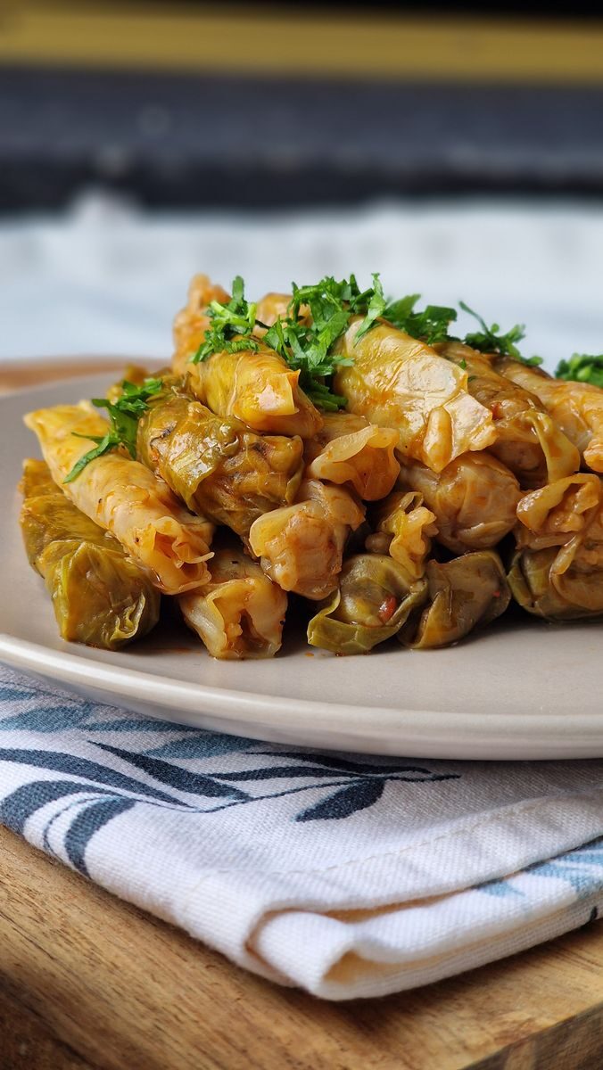 Close-up of traditionally cooked stuffed cabbage rolls garnished with parsley on a plate.