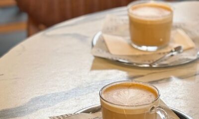 Two frothy cappuccinos on a marble cafe table, set for a cozy coffee break.
