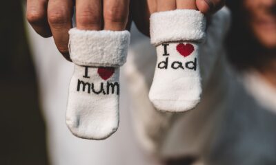 Adorable baby socks with 'I love mum' and 'I love dad' messages held by parents' hands. Perfect for family themes.