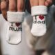 Adorable baby socks with 'I love mum' and 'I love dad' messages held by parents' hands. Perfect for family themes.