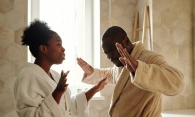 A couple in bathrobes having an emotional discussion in an indoor setting with expressive hand gestures.