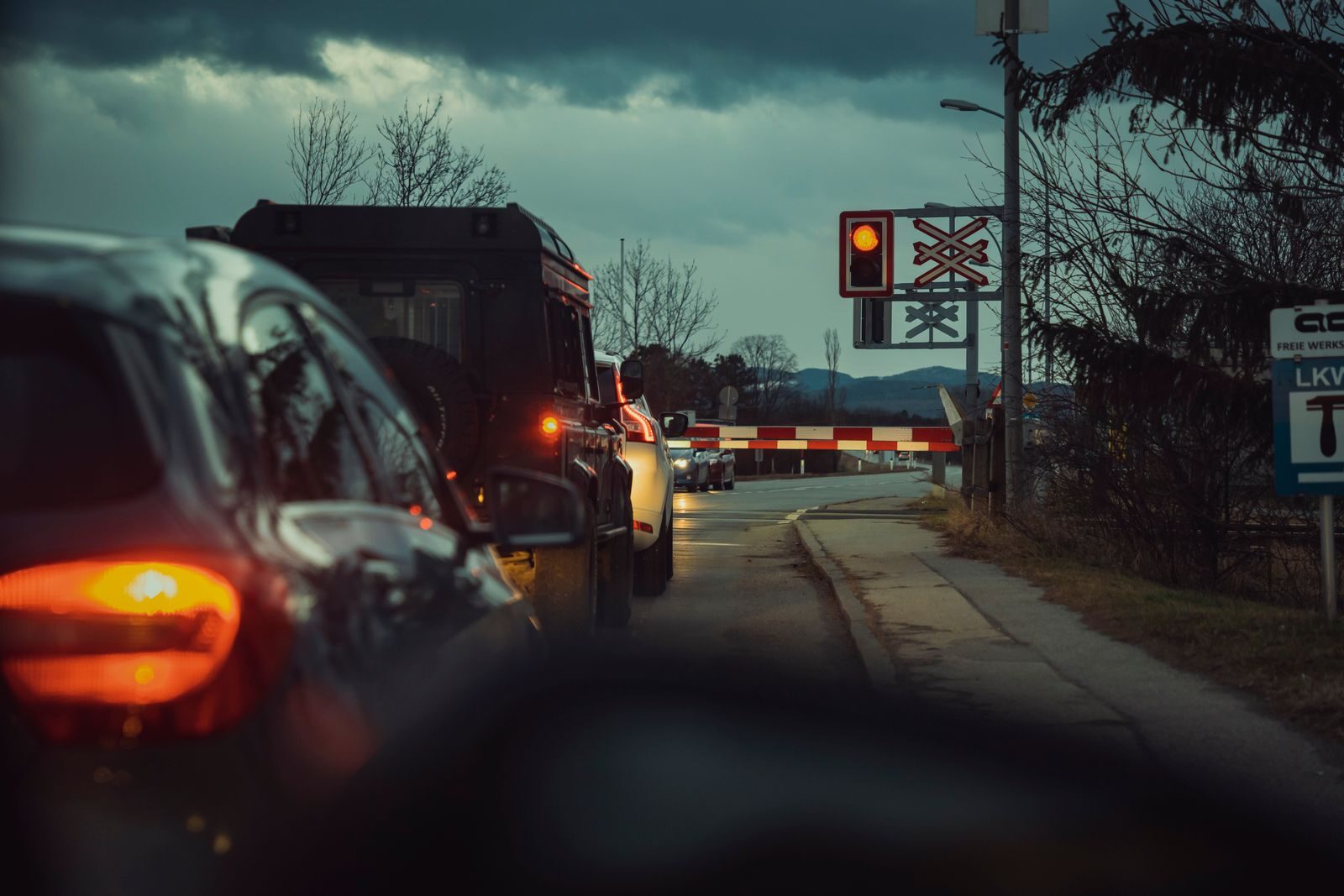 A line of cars waiting at a railway crossing during the night, showcasing urban transportation.