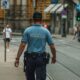 A police officer walking down a city street during the day, maintaining law and order.