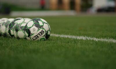 Close-up view of soccer balls lined up on a grassy football field.