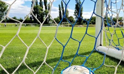 Vibrant shot of a soccer ball trapped in the goal net on a sunny day.