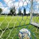 Vibrant shot of a soccer ball trapped in the goal net on a sunny day.