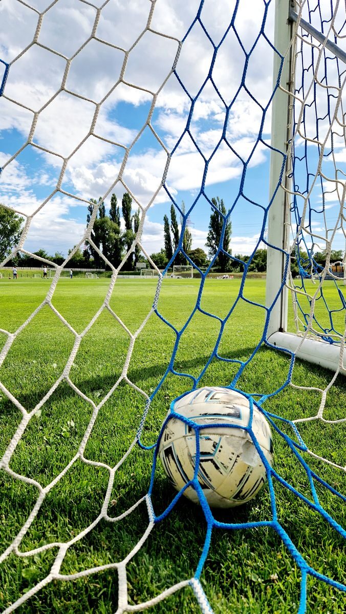 Vibrant shot of a soccer ball trapped in the goal net on a sunny day.