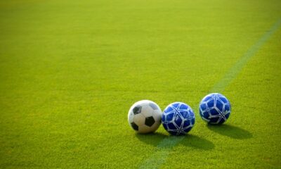Three soccer balls positioned on a vibrant green field in the afternoon sun, perfect for sports themes.