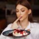Woman savoring a dessert with fruit syrup, showcasing delightful treats.