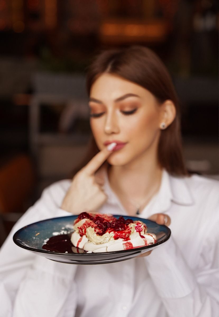 Woman savoring a dessert with fruit syrup, showcasing delightful treats.
