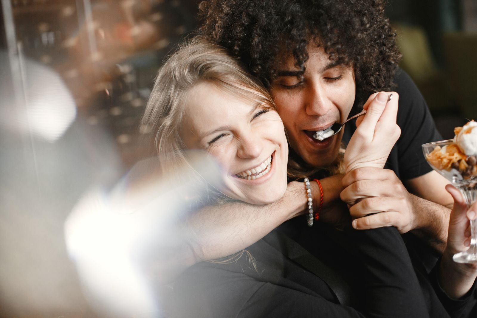 A joyful moment of a couple laughing and sharing a dessert, highlighting togetherness and love.