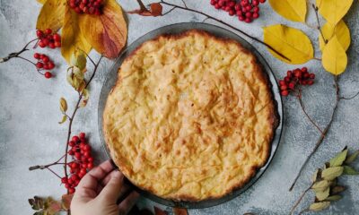 Freshly baked pie surrounded by autumn leaves and rowanberries on a rustic table.