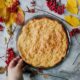 Freshly baked pie surrounded by autumn leaves and rowanberries on a rustic table.