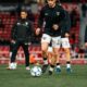 Soccer players in black jerseys warming up on a stadium field pre-match.