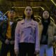 From below of young Asian friends in stylish clothes standing on street under roof with bright illumination