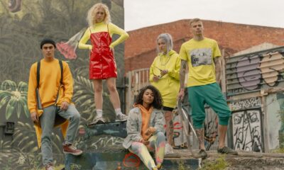 Fashionable group posing in vibrant street style against graffiti mural backdrop.