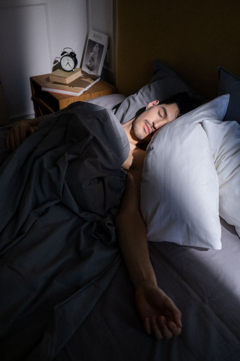 A man sleeps peacefully in a sunlit bedroom, with soft shadows cast on his face.
