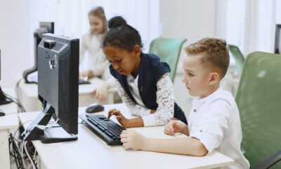 Diverse children working together on computers in a modern school setting.