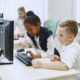 Diverse children working together on computers in a modern school setting.