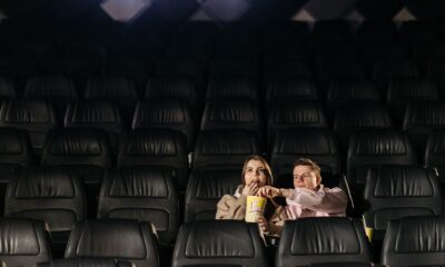 A couple enjoying a movie date with popcorn in an empty theater.