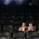 A couple enjoying a movie date with popcorn in an empty theater.