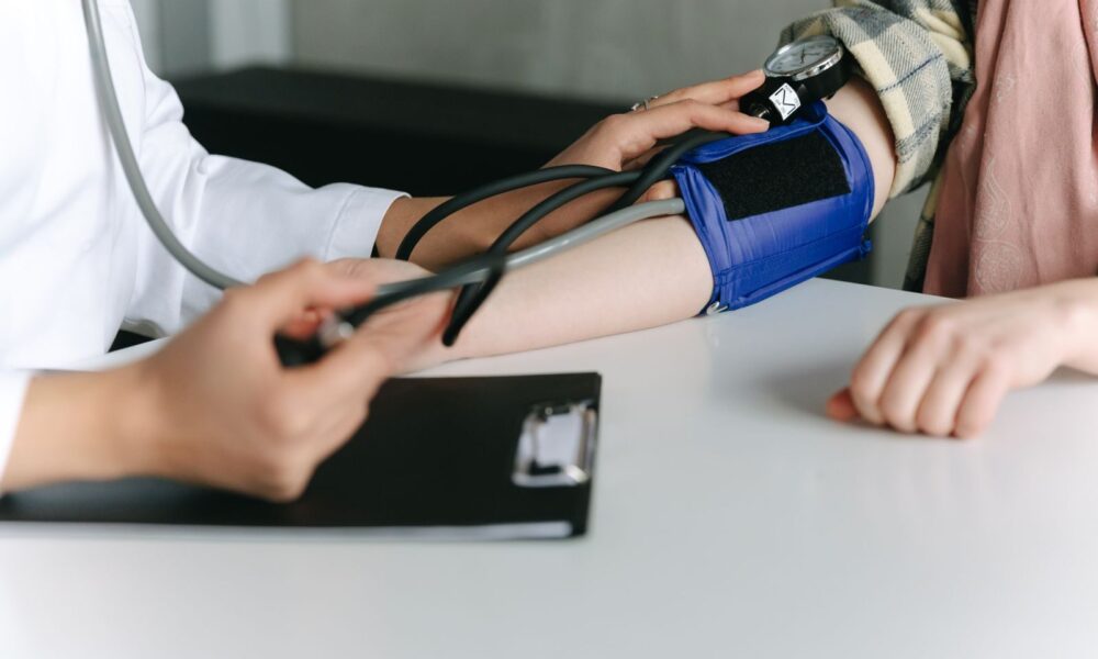 A healthcare worker uses a sphygmomanometer to check a patient's blood pressure in a medical office.
