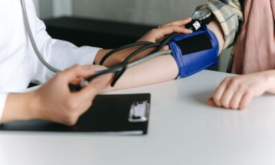 A healthcare worker uses a sphygmomanometer to check a patient's blood pressure in a medical office.
