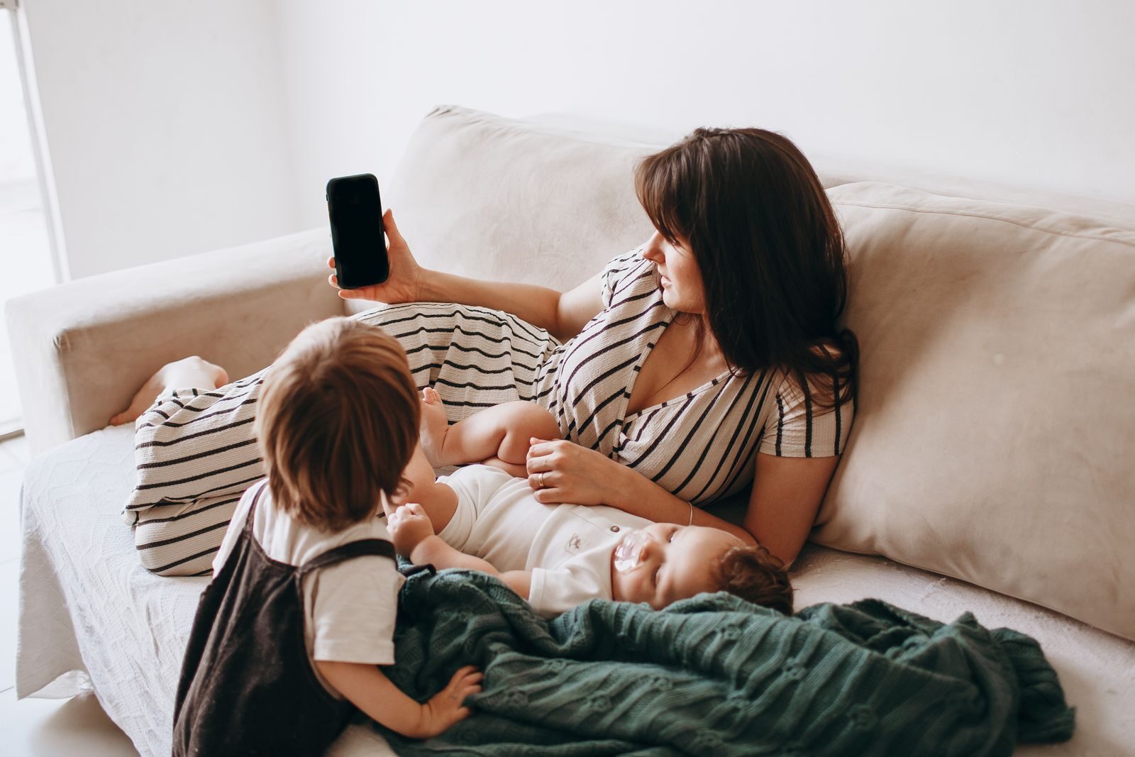 A mother and her children enjoy leisure time on the sofa, highlighting family togetherness and relaxation.