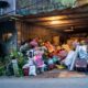 A garage filled with various household items, plants, and clutter overflowing onto the street.