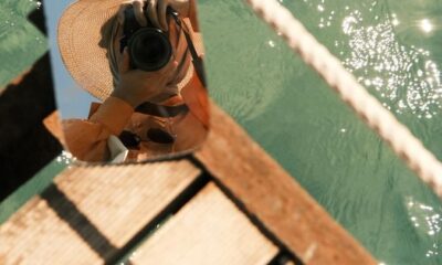 Mirror reflection of a photographer capturing water views from a dock.