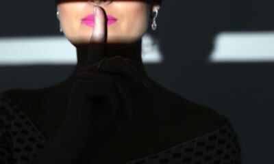 Silhouette of a woman in shadow with finger on lips indicating silence.