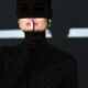 Silhouette of a woman in shadow with finger on lips indicating silence.