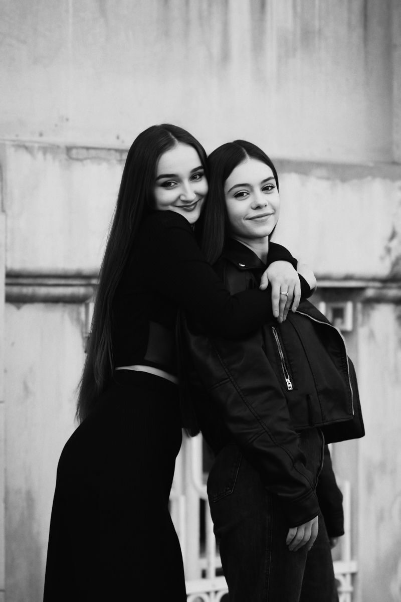 Charming black and white portrait of two young women embracing and smiling, showcasing friendship.