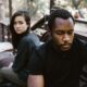 A couple in a serious moment, suggesting conflict or breakup, outdoors.