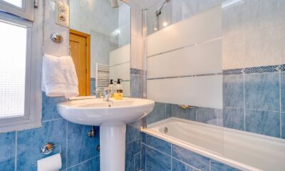 Bright minimalist bathroom with modern blue tiles, glass shower, and a clean white sink.