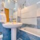 Bright minimalist bathroom with modern blue tiles, glass shower, and a clean white sink.