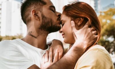 A loving couple shares a tender kiss under city trees, embodying youthful romance.