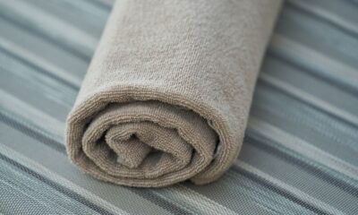 Close-up of a soft beige cotton towel rolled neatly on a striped fabric surface. Perfect for home decor or textile themes.