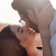A loving couple shares an intimate moment outdoors at sunset.