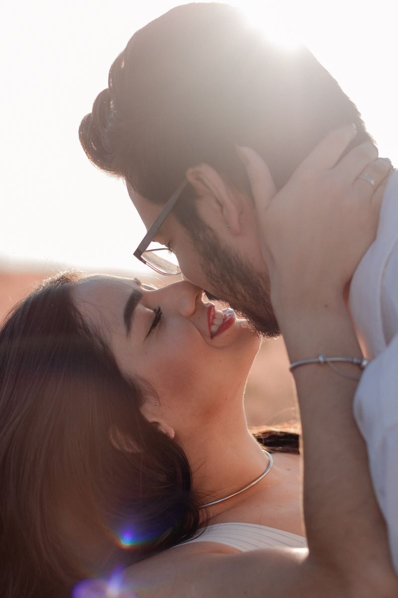 A loving couple shares an intimate moment outdoors at sunset.