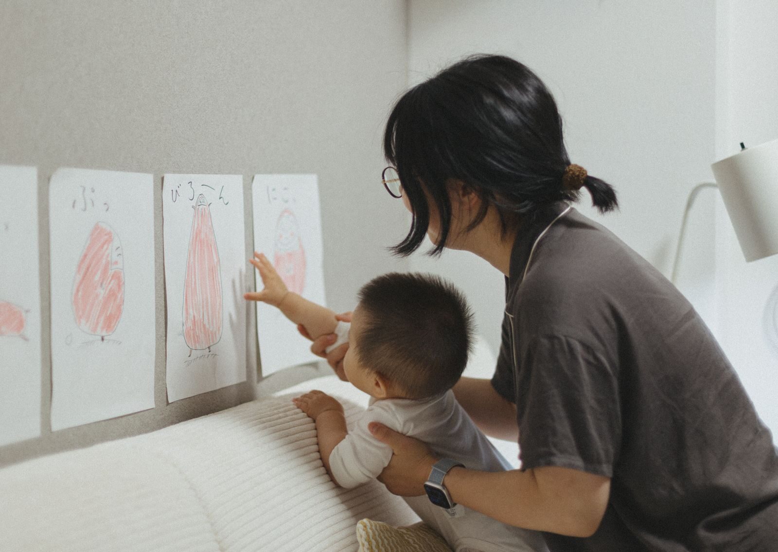 A mother and child engage in a learning activity, exploring art drawings in a cozy indoor setting.