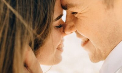 Close-up of a smiling couple sharing a romantic moment outdoors in daylight.