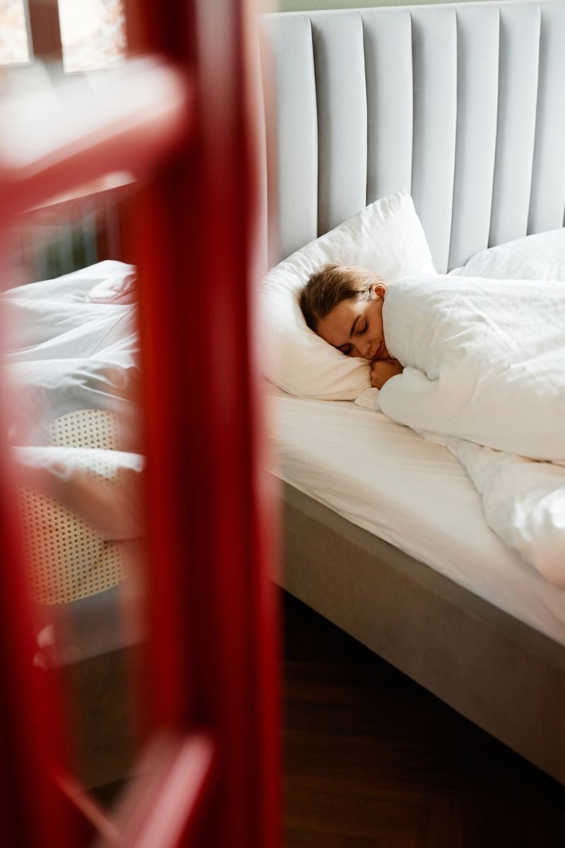 A woman enjoys a restful sleep on a comfortable bed in a tranquil bedroom setting.