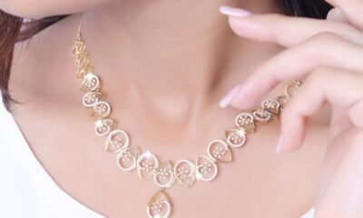 Close-up of a model wearing a stylish gold necklace against a soft background.