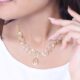 Close-up of a model wearing a stylish gold necklace against a soft background.
