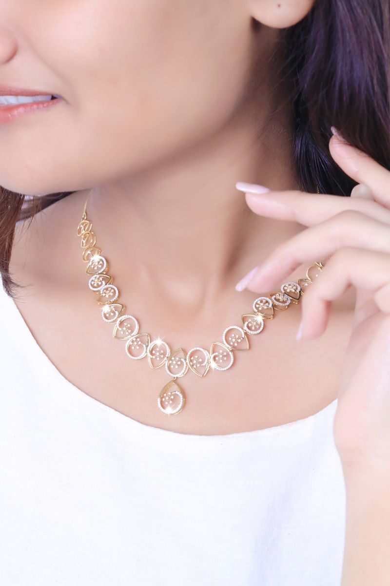 Close-up of a model wearing a stylish gold necklace against a soft background.
