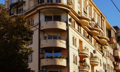 A classic architectural residential building with balconies in a city setting under a clear blue sky.