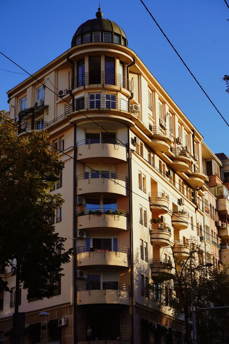A classic architectural residential building with balconies in a city setting under a clear blue sky.