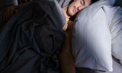 A man sleeps peacefully in a sunlit bedroom, with soft shadows cast on his face.